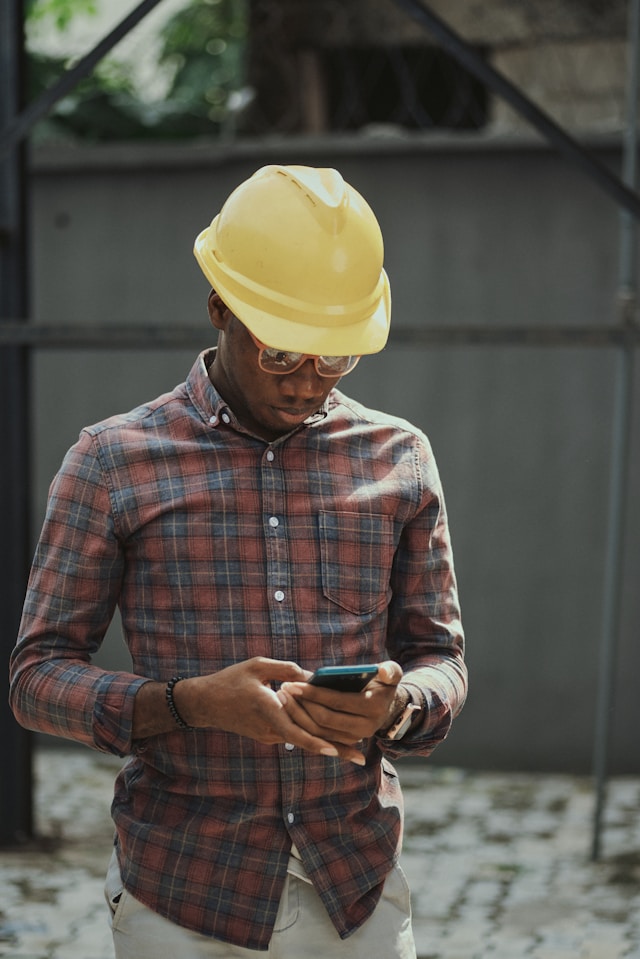 An engineer in a hard hat checking his phone on site